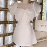 Đầm trắng tay phồng nơ ngực đính đá thân